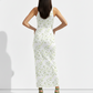 A sleeveless white bodycon maxi dress patterned with delicate green leaf motifs for a fresh, light, and nature-inspired look.