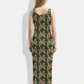 A sleeveless dark green bodycon maxi dress featuring a repeating blush pink abstract leaf pattern for a chic, modern, and playful look.