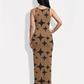 An elegant sleeveless bodycon maxi dress featuring a warm camel base with bold black starburst geometric prints, creating a chic, modern, and eye-catching statement look.