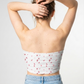 A white strapless tube top featuring a delicate scattered pattern of small dusty pink abstract petal-like shapes for a soft, minimalist look.
