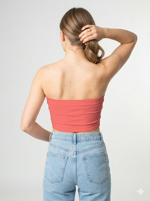 A minimalist strapless tube top in a soft coral pink with a smooth, clean, and vibrant finish.